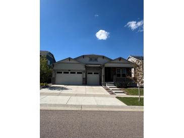 Charming home featuring a stone facade, three-car garage, a small front porch, and well-manicured landscaping at 8163 S Valleyhead Way, Aurora, CO 80016