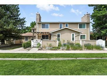 Charming townhome featuring a stone chimney, well-kept lawn, and inviting curb appeal at 8422 Everett Way # C, Arvada, CO 80005