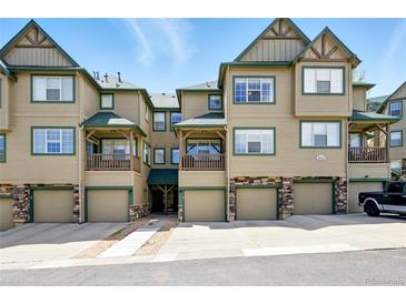Inviting townhome complex with private garages, covered decks and charming stone accents against blue skies at 31112 Black Eagle Dr # 103, Evergreen, CO 80439