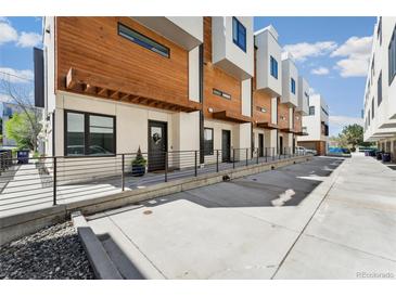 Modern townhomes with wood and white exteriors line a concrete walkway with wrought iron railing at 3414 W 18Th Ave, Denver, CO 80204