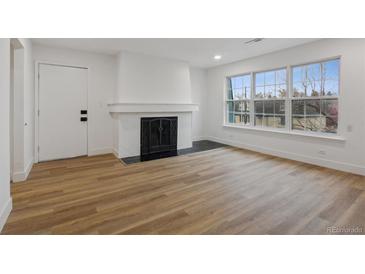 Bright living room with wood floors, fireplace, and large windows at 9120 E Girard Ave # 12, Denver, CO 80231