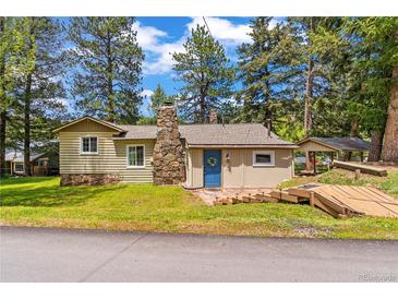 Charming single Gathering home featuring a stone chimney, blue front door, and wooden walkway at 26351 Sheldon St, Kittredge, CO 80457