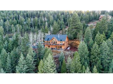 Stunning log home surrounded by lush evergreens, featuring a large deck and a private, wooded setting at 1055 Saddleback Dr, Evergreen, CO 80439