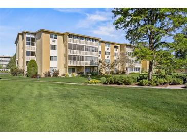 Low-rise condominium with manicured green lawn, lush shrubs, and mature trees at 610 S Alton Way # 7C, Denver, CO 80247