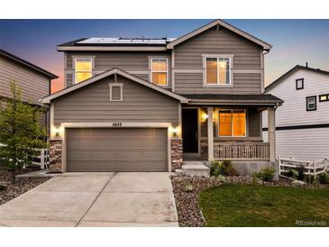 Inviting two-story home featuring a covered porch, stone accents, a two car garage, and solar panels at 2633 Garganey Dr, Castle Rock, CO 80104