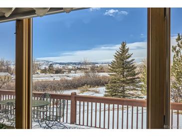 A view from the deck, with an outdoor table and chairs set and a snowy mountainscape in the distance at 1901 Blue Mountain Ave, Berthoud, CO 80513