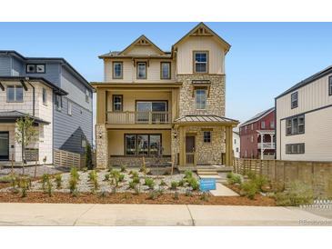 New build home with a stone and tan siding exterior, balcony, and small landscaped front yard at 7276 Waterleaf Trl, Littleton, CO 80125