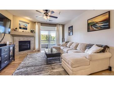 Bright living room with a cozy fireplace, plush sectional sofa and a sliding glass door with a balcony at 8445 S Holland Way # 205, Littleton, CO 80128