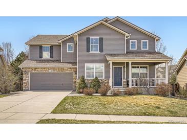 Charming two-story home with gray siding, stone accents, and a well-maintained lawn at 12185 S Grass River Trl, Parker, CO 80134