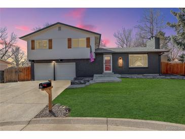 Charming two-story home with a well-manicured lawn and a brick exterior at dusk at 8229 Marshall Ct, Arvada, CO 80003