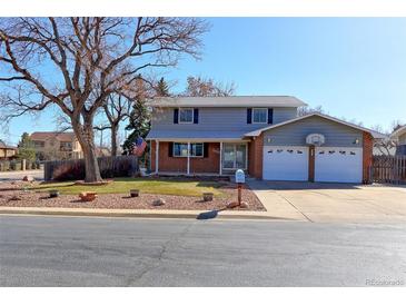 Two story home featuring a large front yard with mature trees and two car garage with basketball hoop at 9202 W Virginia Pl, Lakewood, CO 80226