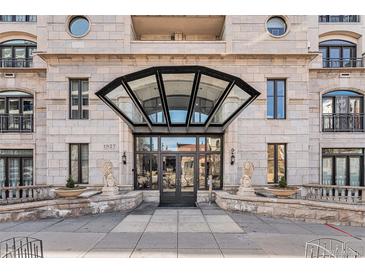 Grand building entrance featuring lion statues, covered glass entry, stone facade, and wrought iron balcony railing at 1827 N Grant St # 1104, Denver, CO 80203