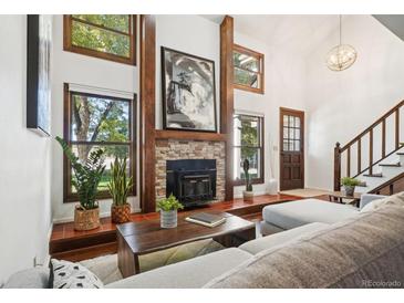 Bright living room with vaulted ceiling, fireplace, and hardwood floors at 2103 Ranch Dr, Westminster, CO 80234