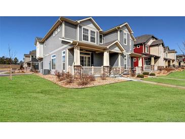 Charming gray two-story home with stone accents, covered porch, and well-manicured lawn on a sunny day at 17851 E 103Rd Ave, Commerce City, CO 80022