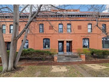 Charming brick townhouse featuring a symmetrical facade, iron fencing, and well-kept landscaping at 1748 W 36Th Ave, Denver, CO 80211