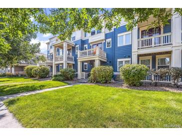 Beautiful blue townhome featuring a well-manicured lawn and private balconies at 9484 E 108Th Ave, Commerce City, CO 80640