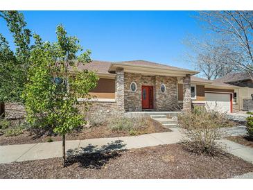 Charming single-story home with a stone facade, red front door and well-maintained landscaping at 1155 S Balsam St, Lakewood, CO 80232