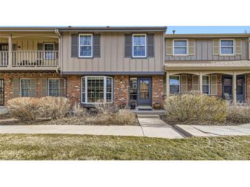 Charming townhouse featuring a brick facade, bay window, and landscaped front yard at 8862 E Amherst Dr # D, Denver, CO 80231