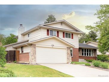 Charming two-story home features a two car garage, stone accents, brick details, and a well-manicured lawn at 7328 S Kit Carson St, Centennial, CO 80122