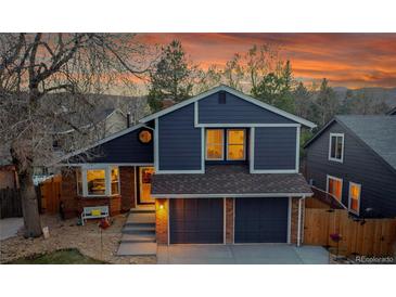 Charming two-story home with a brick and siding exterior and a two-car garage, showcasing its curb appeal at 10866 W Half Moon Pass, Littleton, CO 80127