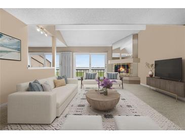 Bright living room featuring a fireplace, access to a balcony, and neutral-toned furniture with a decorative rug at 7160 W Stetson Pl # 27, Littleton, CO 80123