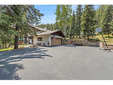 Charming home featuring an expansive driveway and basketball hoop with lush landscaping and a multi-car garage at 34498 Forest Estates Rd, Evergreen, CO 80439