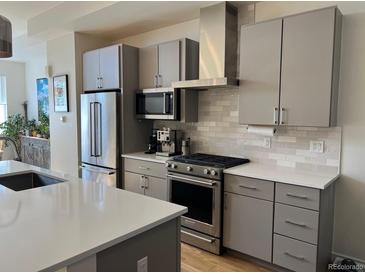 Modern kitchen featuring gray cabinets, stainless steel appliances, and a white countertop island at 1284 Osceola St, Denver, CO 80204