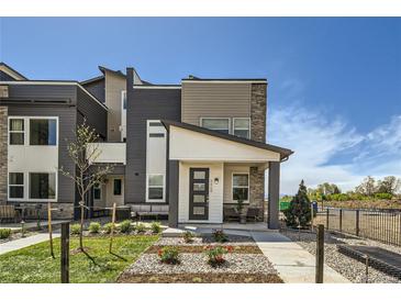 Modern townhome with stone accents, a covered porch, and professionally landscaped front yard at 6864 Bryant Ct, Denver, CO 80221