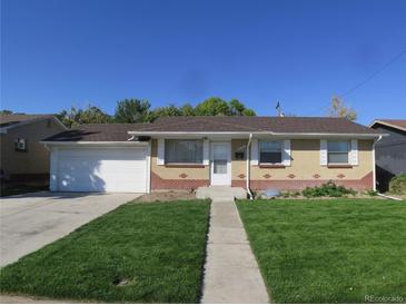 Charming brick home with a well-manicured lawn and an attached garage under a clear blue sky at 6741 Leyden St, Commerce City, CO 80022