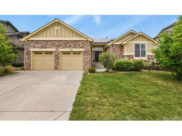 Charming two-story home with stone accents, a well-manicured lawn, and a two car attached garage at 297 N Coolidge Way, Aurora, CO 80018