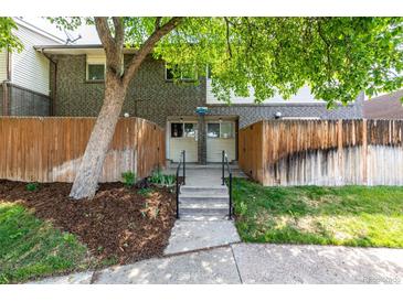 Charming townhouse featuring a brick facade, fenced-in front yard, and landscaped entrance at 8023 Wolff St # C, Westminster, CO 80031