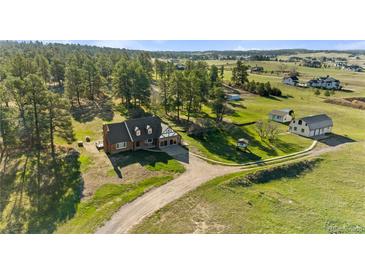 Aerial view of a charming brick home featuring a well-manicured yard and quaint outbuildings at 10522 Bayou Gulch Rd, Parker, CO 80134