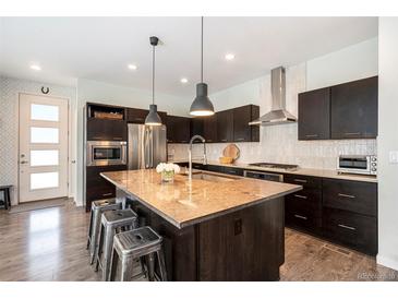 Modern kitchen featuring stainless steel appliances, dark wood cabinetry, and a large center island with seating at 9603 Dunning Cir, Highlands Ranch, CO 80126
