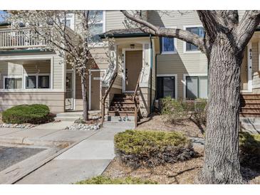 Inviting townhouse entrance with wood stairs and neutral siding complemented by mature trees and landscaping at 8707 E Florida Ave # 814, Denver, CO 80247