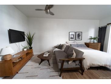 Bright and airy bedroom featuring a seating area, ceiling fan, and a comfortable bed with stylish decor at 215 E 11Th Ave # A5, Denver, CO 80203