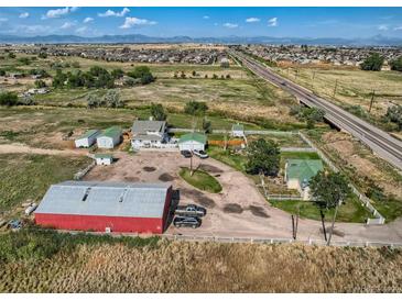An aerial view of an expansive property featuring multiple buildings, fenced yards, and a barn at 3550 E 160Th Ave, Thornton, CO 80602