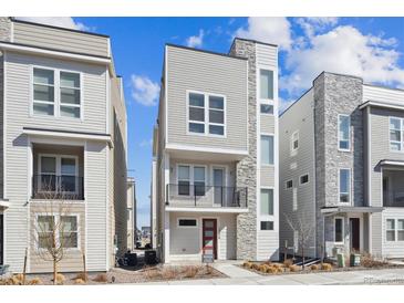 Modern three-story home with a balcony, stylish stonework, and neutral-colored siding at 12270 Karls Ln, Northglenn, CO 80241