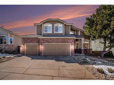 Charming two-story home featuring a brick facade and a well-manicured front yard at sunset at 3336 White Oak Ln, Highlands Ranch, CO 80129