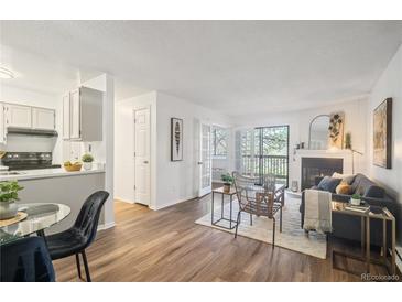 Bright living room featuring modern fireplace, balcony access, and wood-look flooring at 14751 E Tennessee Dr # 228, Aurora, CO 80012