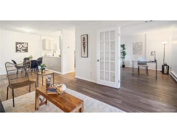 Open living room showcasing hardwood floors, stylish furnishings, and abundant natural light, flowing into adjacent office and kitchen at 14751 E Tennessee Dr # 228, Aurora, CO 80012