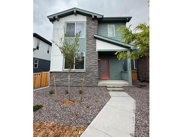 Charming two-story home with gray stone and colorful exterior featuring a red door and rock landscaping at 21011 E 63Rd Dr, Aurora, CO 80019