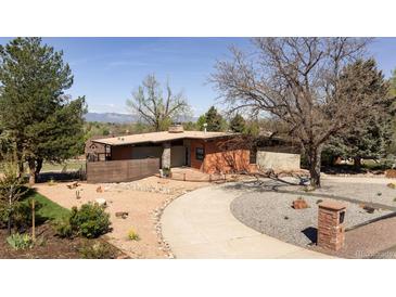 A modern, single-story home boasts a unique design and meticulously landscaped front yard with a mountain view at 8 Lindenwood Dr, Littleton, CO 80120
