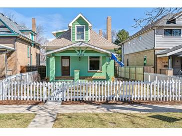 Charming green home featuring a peaked roof and a classic white picket fence at 4054 Wyandot St, Denver, CO 80211