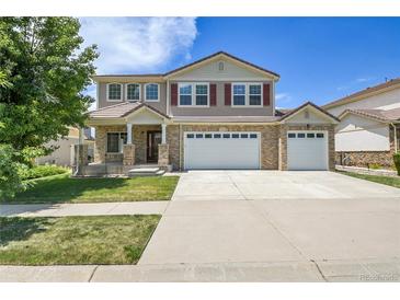 Charming two-story home featuring a three car garage, landscaped lawn, and brick accents, with great curb appeal at 5131 Netherland St, Denver, CO 80249