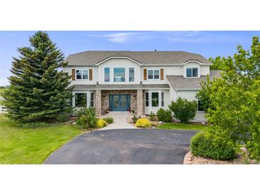 Charming two-story home showcasing a manicured lawn, brick entryway and blue double doors at 46093 Bristlecone Ct, Parker, CO 80138