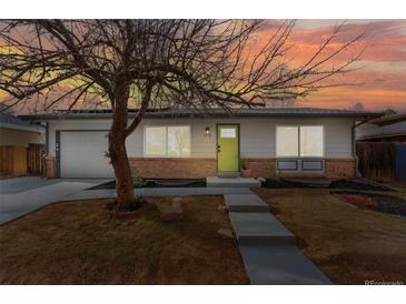 Charming single-story home with a well-manicured lawn, brick accents, and a vibrant green front door under a sunset sky at 1515 Sagrimore Cir, Lafayette, CO 80026