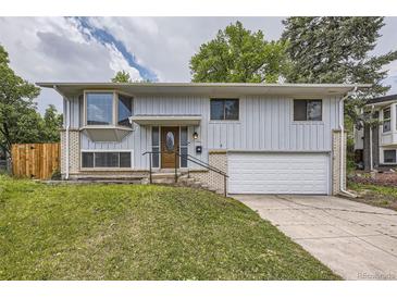 Charming home with light gray siding, brick accents, well-kept lawn, and a convenient two-car garage at 1477 S Wright St, Lakewood, CO 80228