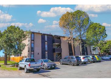 Multi-level apartment building with a parking lot and mature trees on a sunny day at 865 S Quebec St # 302A, Denver, CO 80247