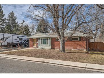 Charming brick home featuring a cozy front yard with mature trees and a small seating area at 7005 S Ash Cir, Centennial, CO 80122