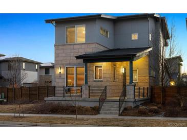 Contemporary home featuring a stone facade, covered porch, and stylish railing at 65 Newport St, Denver, CO 80230